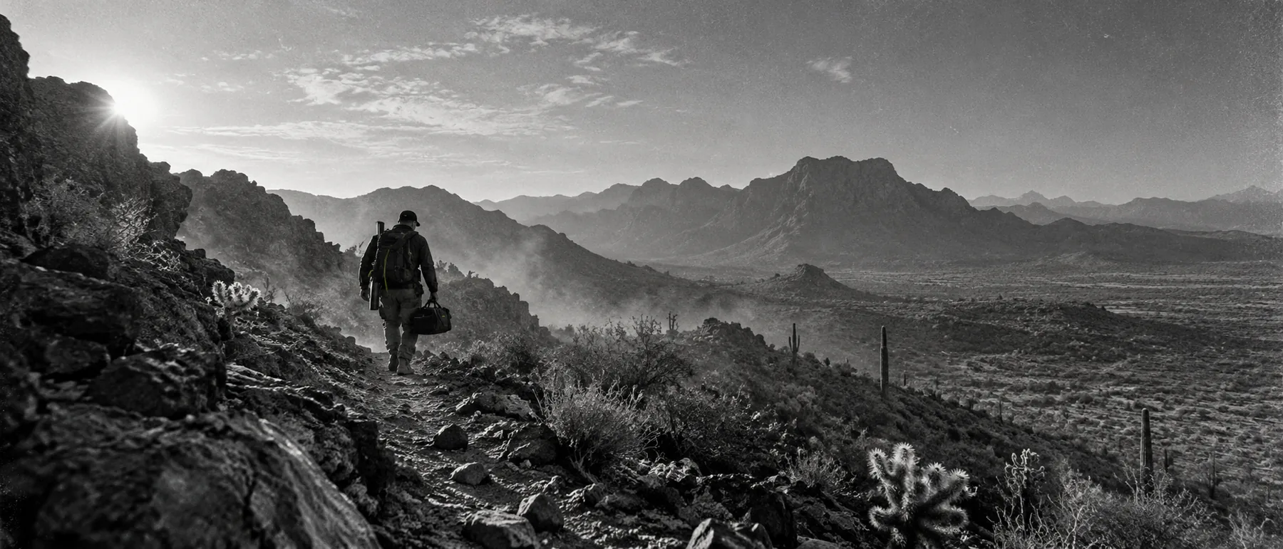A person crossing a rugged Arizona desert landscape